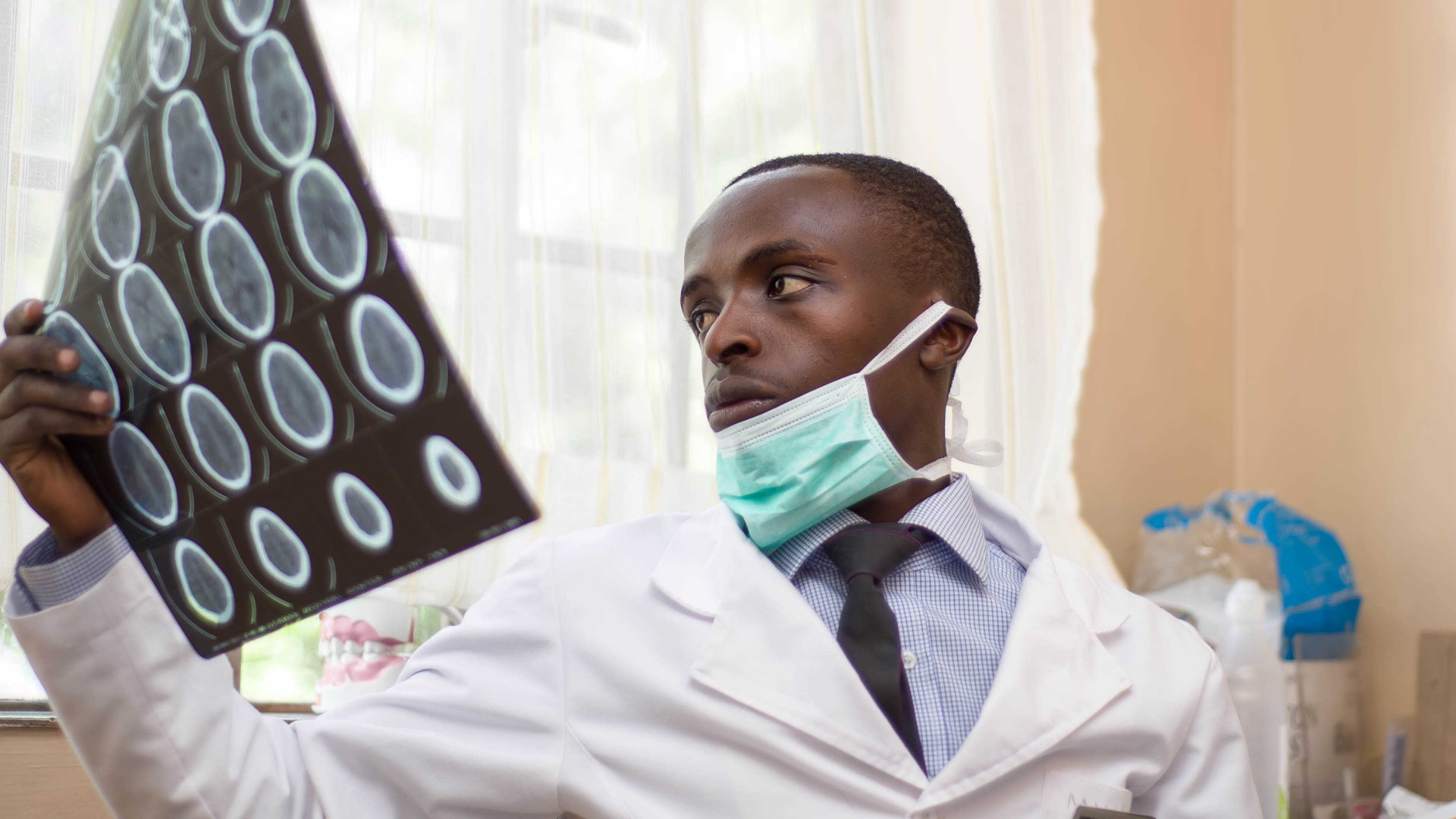 a man in a white coat and mask looking at an x-ray