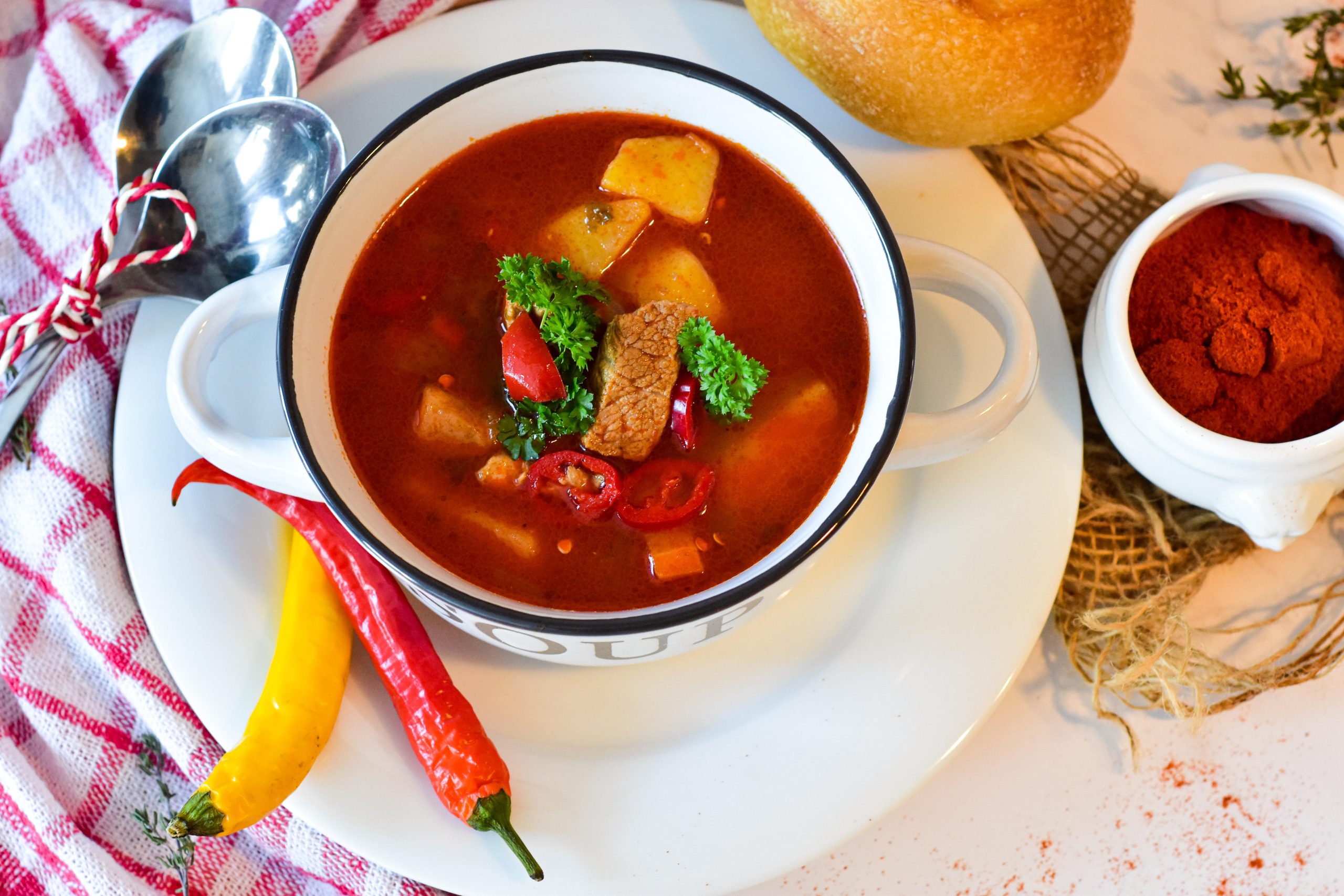 a bowl of soup with vegetables and a spoon on a plate