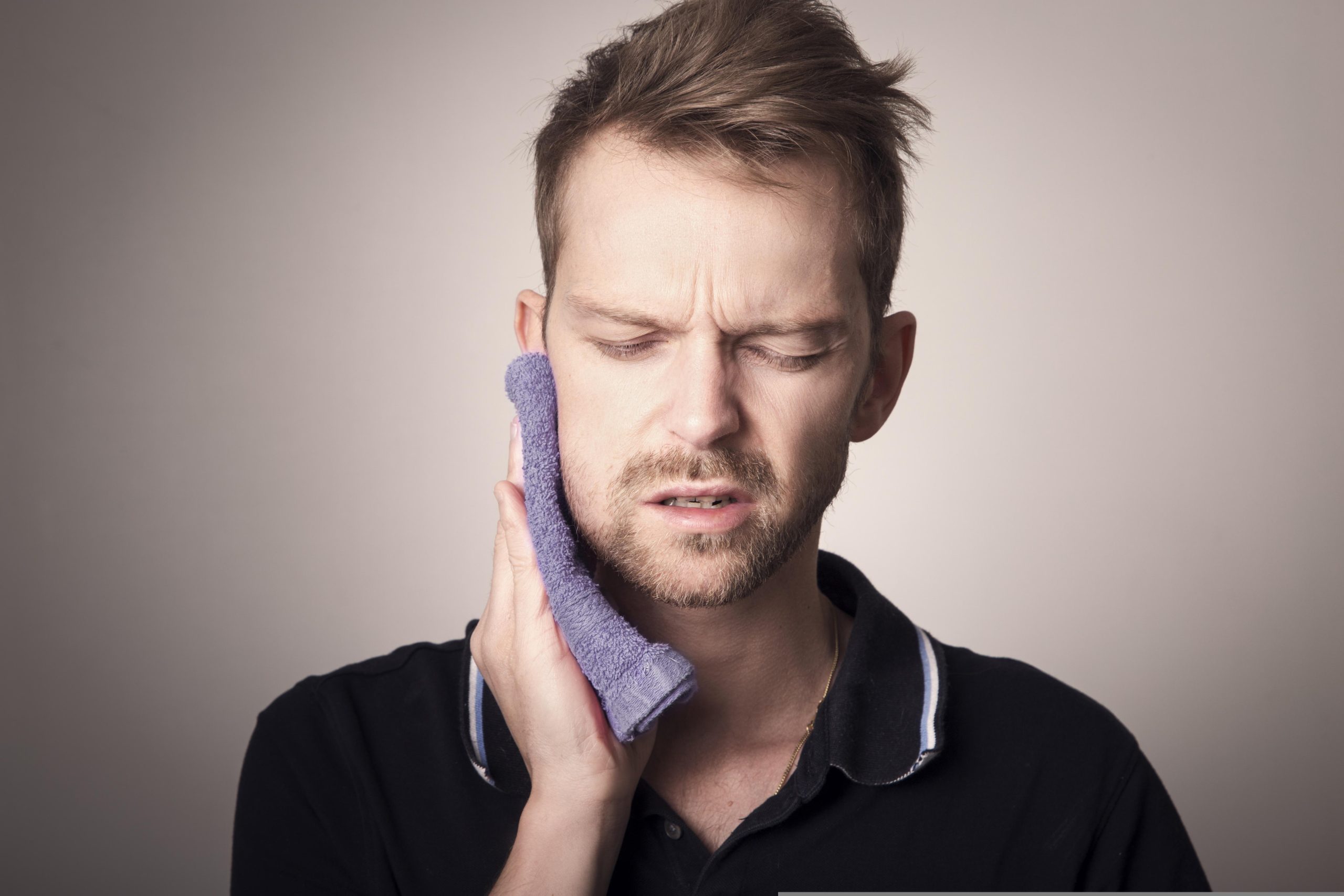 a man EXPERIENCING DENTAL DISCOMFORT with a towel on his face