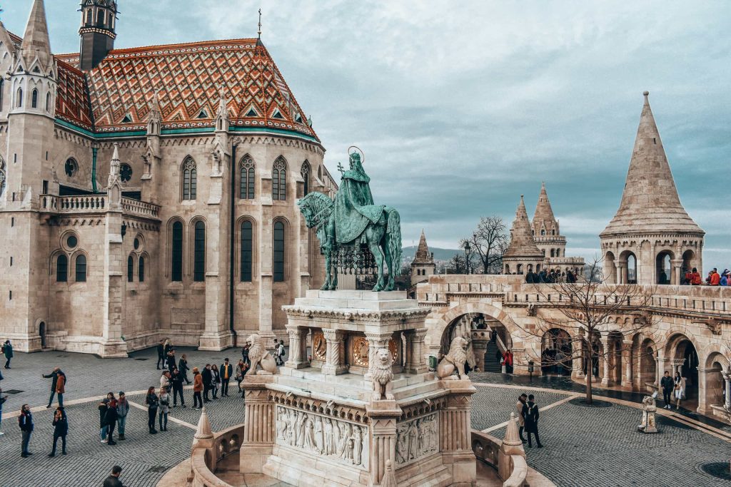 Panoramic view of Budapest’s Matthias Church and Fisherman’s Bastion, featuring the bronze equestrian statue of King Stephen I surrounded by visitors