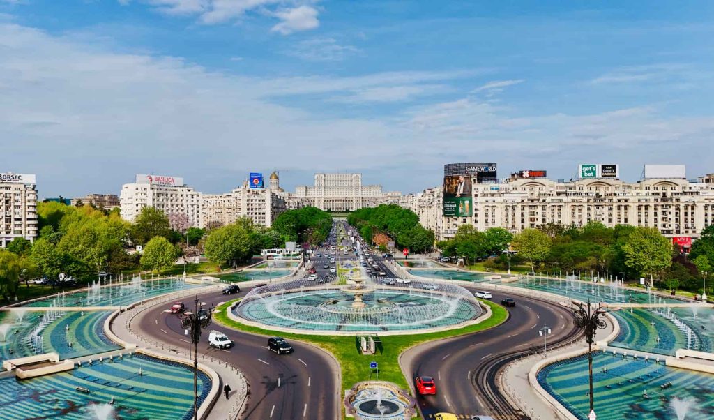 Aerial view of Bucharest featuring the Union Square fountains and the Palace of the Parliament in the background. A popular destination for dental tourism in Romania.