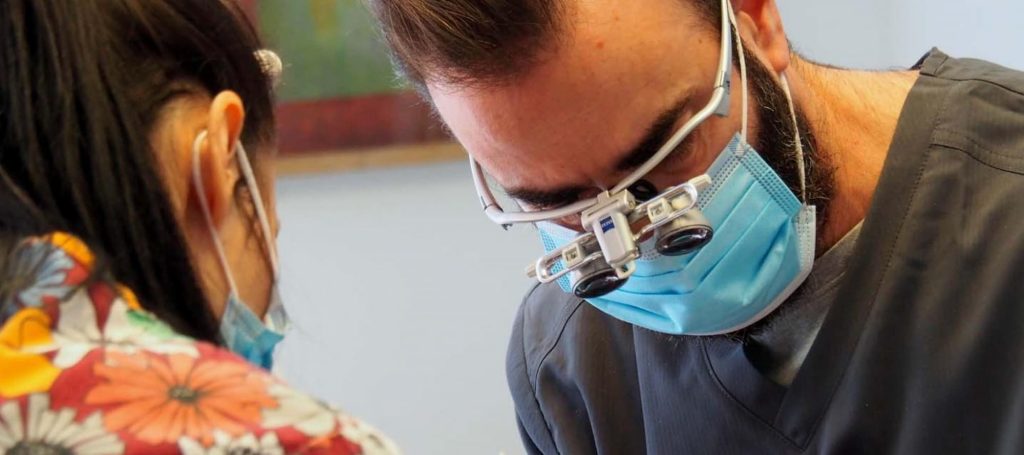 close up picture of dentist with face mask and dental equipment